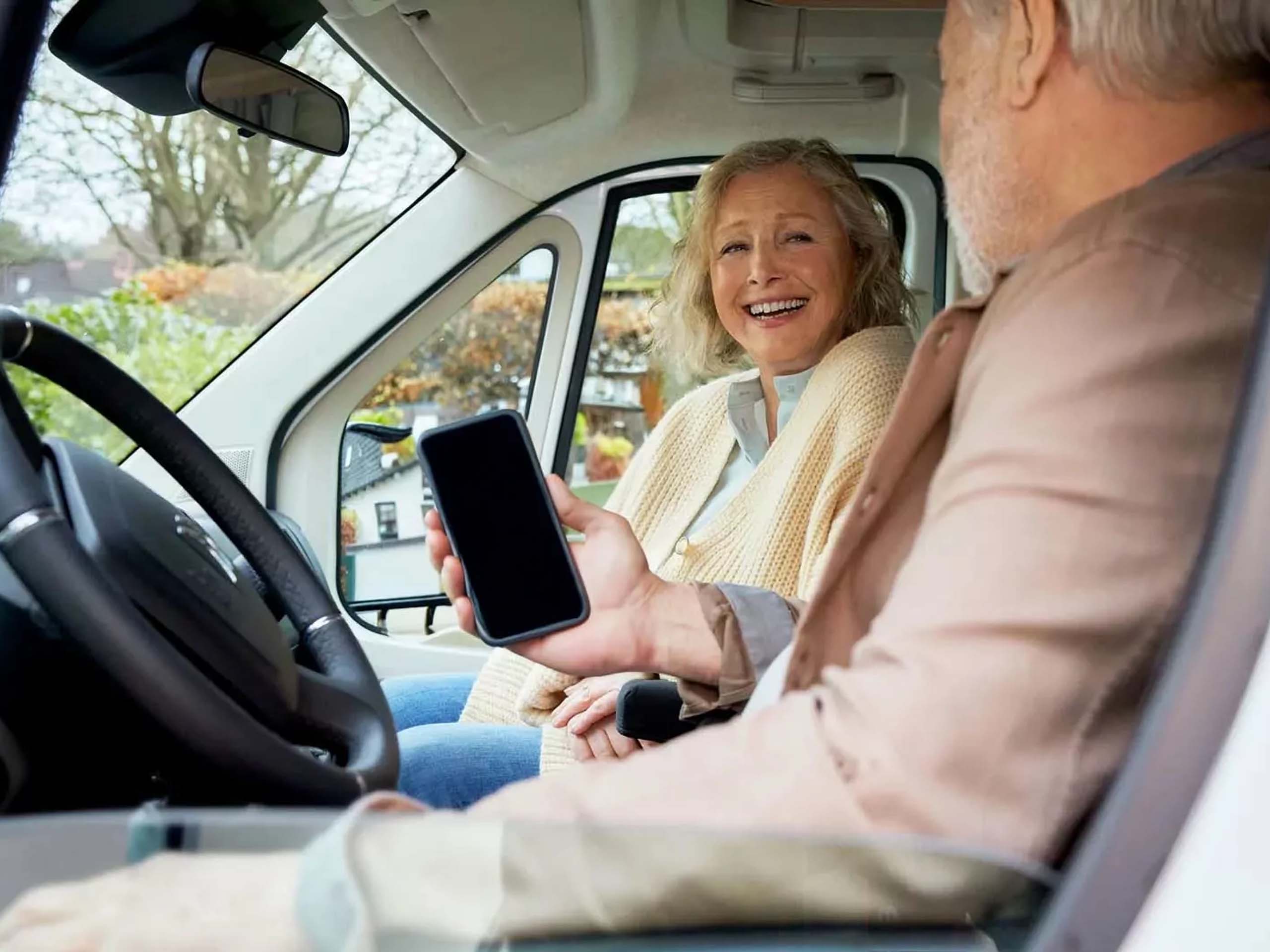 zwei lachende Personen sitzen im Auto